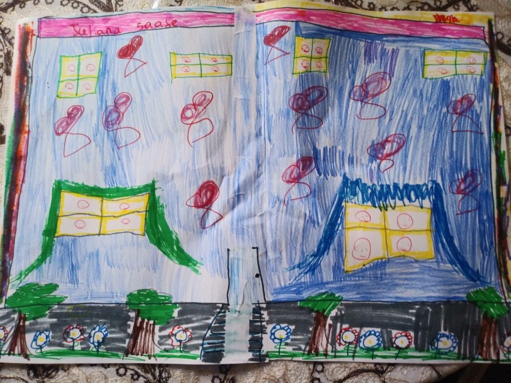 This is a paper that is cooked blue and yellow windows are drawn on it with small happy faces in each window. There are trees and flowers outside of the blue building drawing.