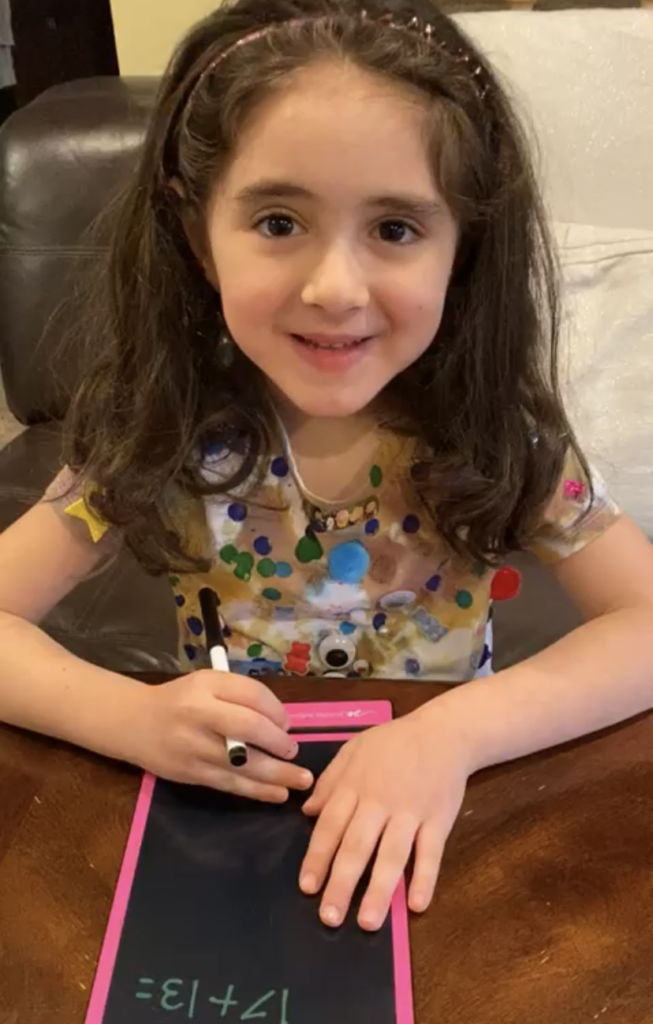 girl wearing a tie dye shirt that has pom poms and shapes glued to it
