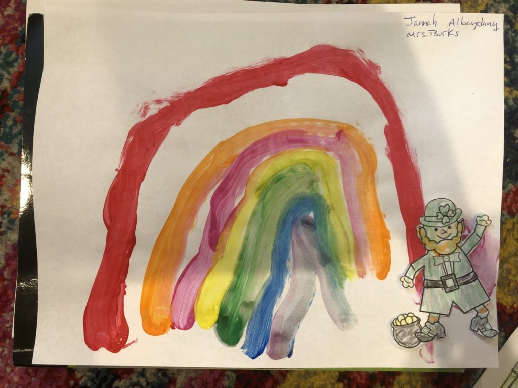 Here is a painting of a rainbow made by a student, there is a leprechaun in the corner