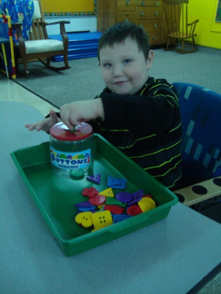 student putting buttons into a jar