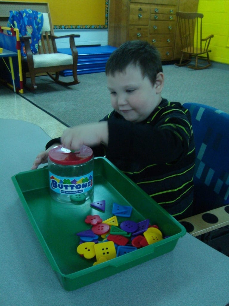 student putting buttons into a jar