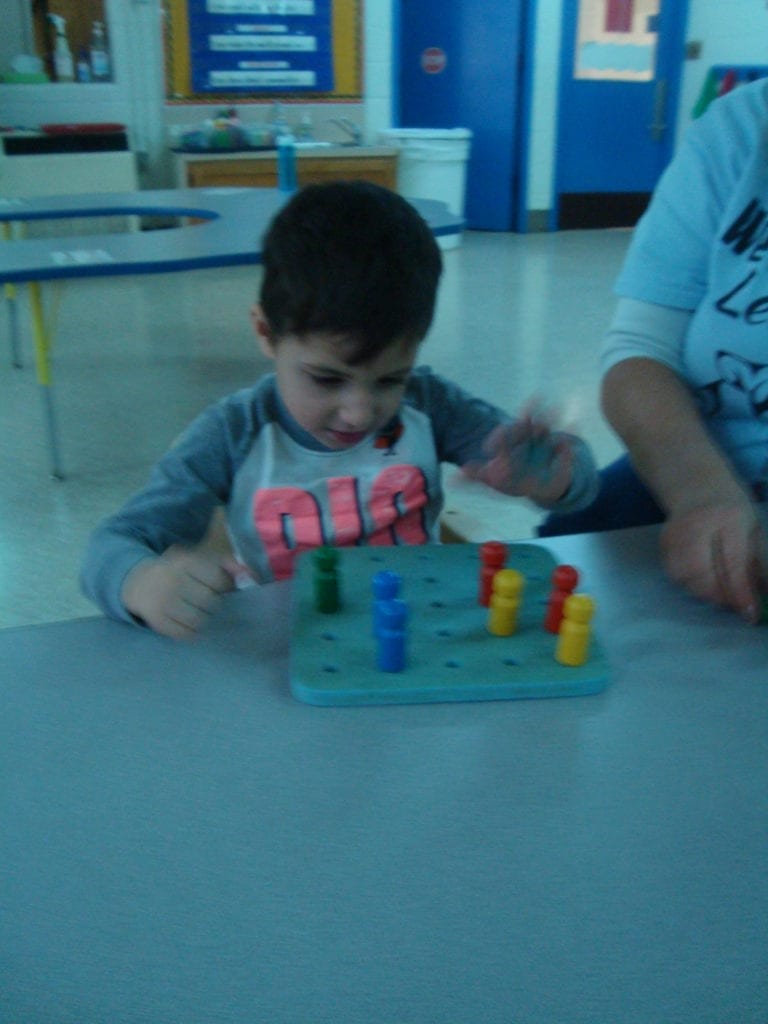 student putting pegs in a peg board