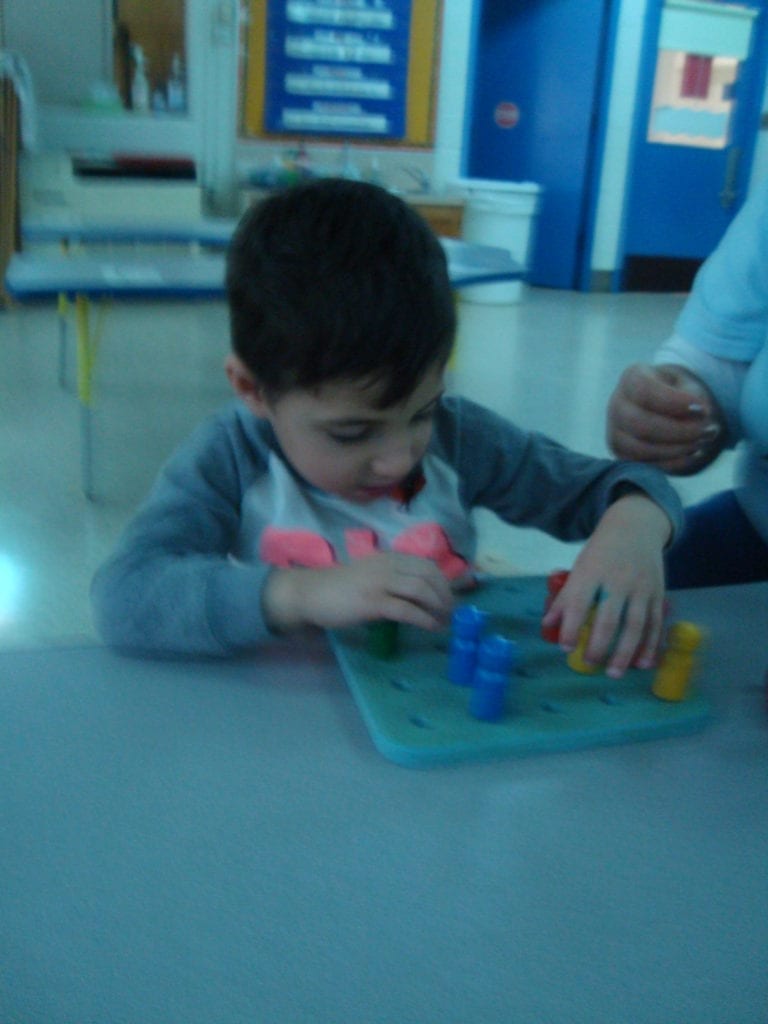 student putting pegs in a peg board