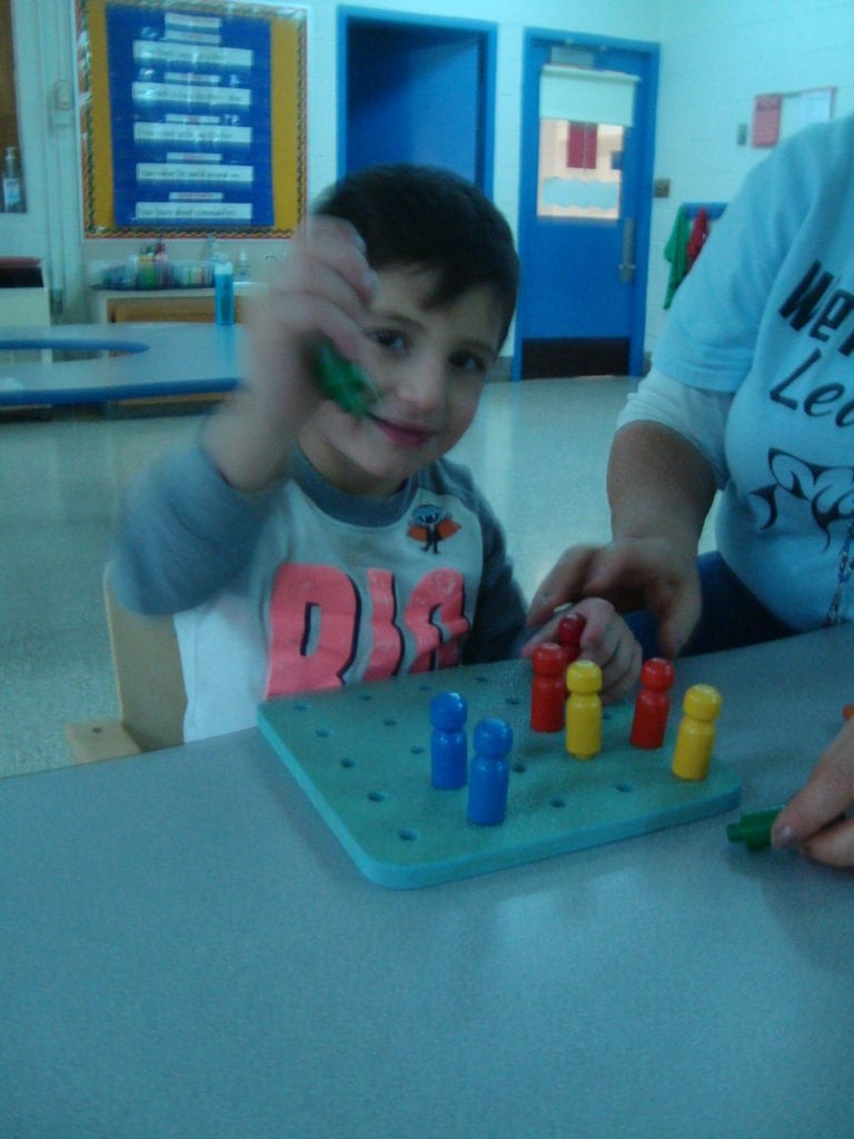 student putting pegs in a peg board