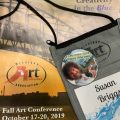 Conference schedule and Bob Ross pin with the words 'let's make happy little trees'