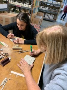 two art teachers carving tiles out of clay