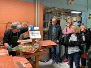 four art teachers watching a demonstration of glazing tiles.