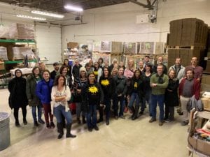 32 art teachers inside Rovin clay warehouse standing in front of pallets of boxes of clay