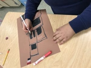 student hands drawing a building from Yemen with a Yemen flag on top