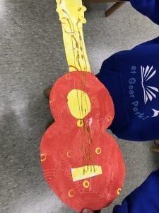 Example of student's paper guitar that is all warm colors with glitter glue stings