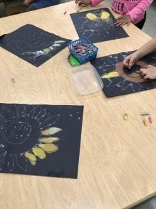 students coloring with chalk inside of their flower drawings