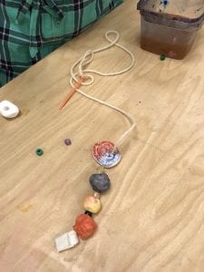student working on threading his beads onto a string with a plastic needle