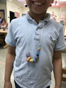student wearing his necklace he made