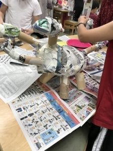 student creating a dinosaur form with newspaper, tape, and cardboard tubes
