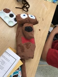in progress monkey paper mache sculpture; student is painting it brown