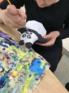 student painting a panda face on her animal with black and white paint