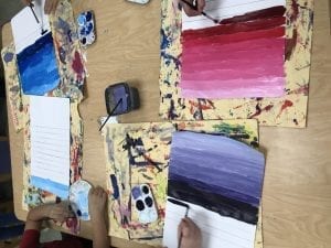 student hands painting value scales; one color but different values of the color that go from light to dark