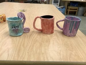 three student made ceramic pieces that look like mugs