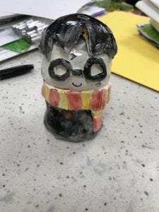 ceramic figuring of Harry Potter with black hair, black glasses, a red and yellow scarf and a black shirt