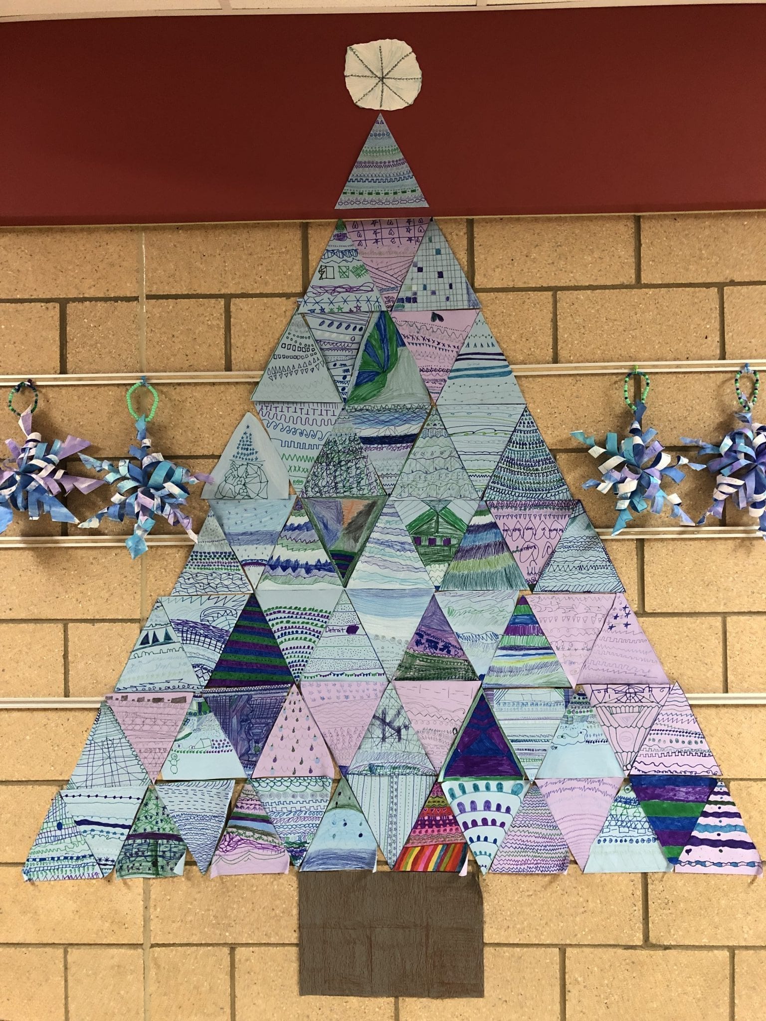 Winter tree made up of triangle paper pieces. Students used mainly purple, green, and blue from the cool color family.