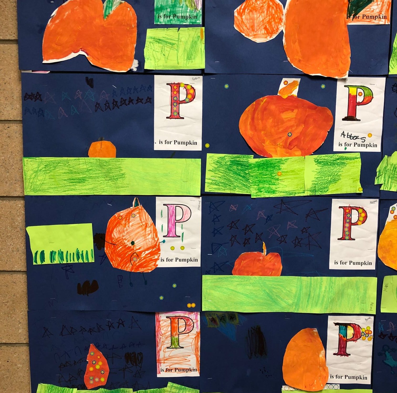 P is for Pumpkin artwork by kindergarten. Painting of a pumpkin glued to a dark blue background with stars and construction paper grass
