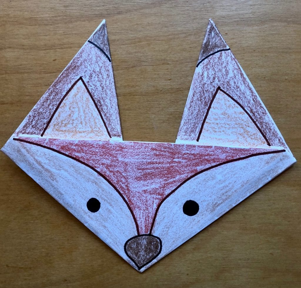 folded paper origami fox colored with different browns and a drawn face