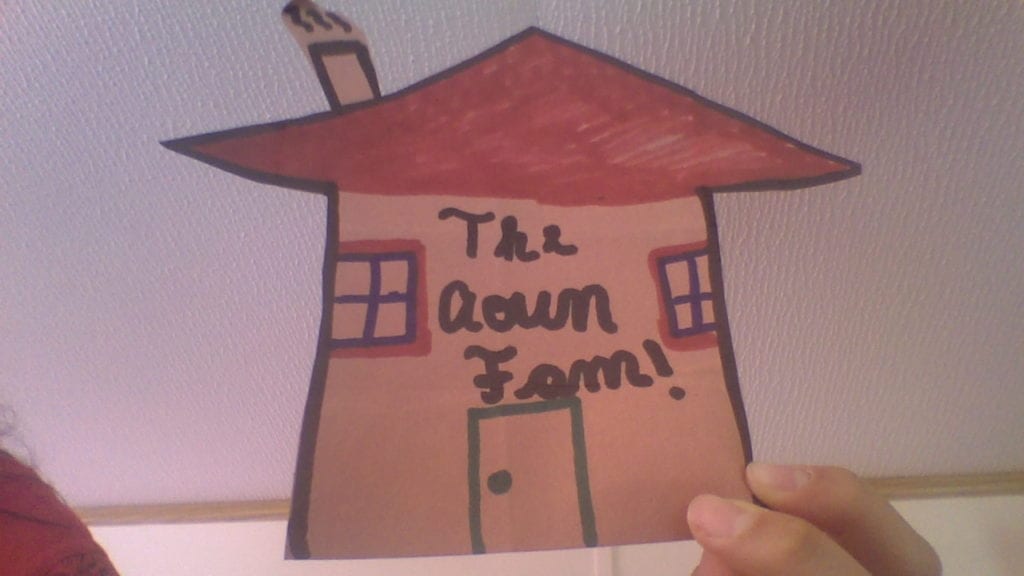 cutout of a house with a door, two windows, a red roof, and chimney