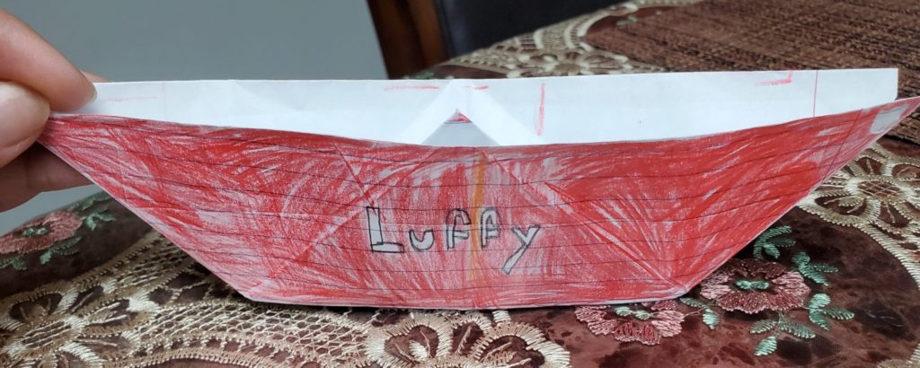 origami boat folded from notebook paper and colored red