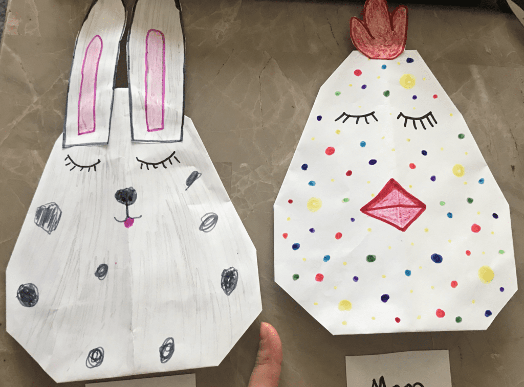 folded paper origami eggs with drawings for a bunny and a chicken