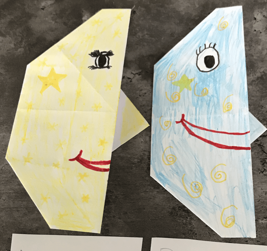 folded paper to make crescent moon shapes with faces and stars drawn on them
