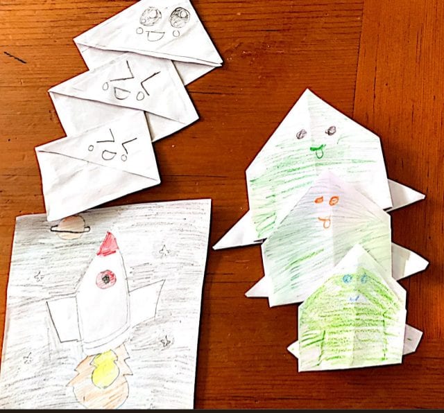 origami folded diamonds with faces on them, origami folded chickens with different faces, and drawing of a rocket