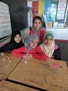Girls creating a pipe cleaner tower.