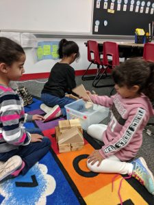 First graders building a house out of blocks.
