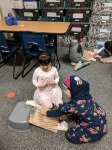 Students using push pins to prevent a ball from hitting the houses.