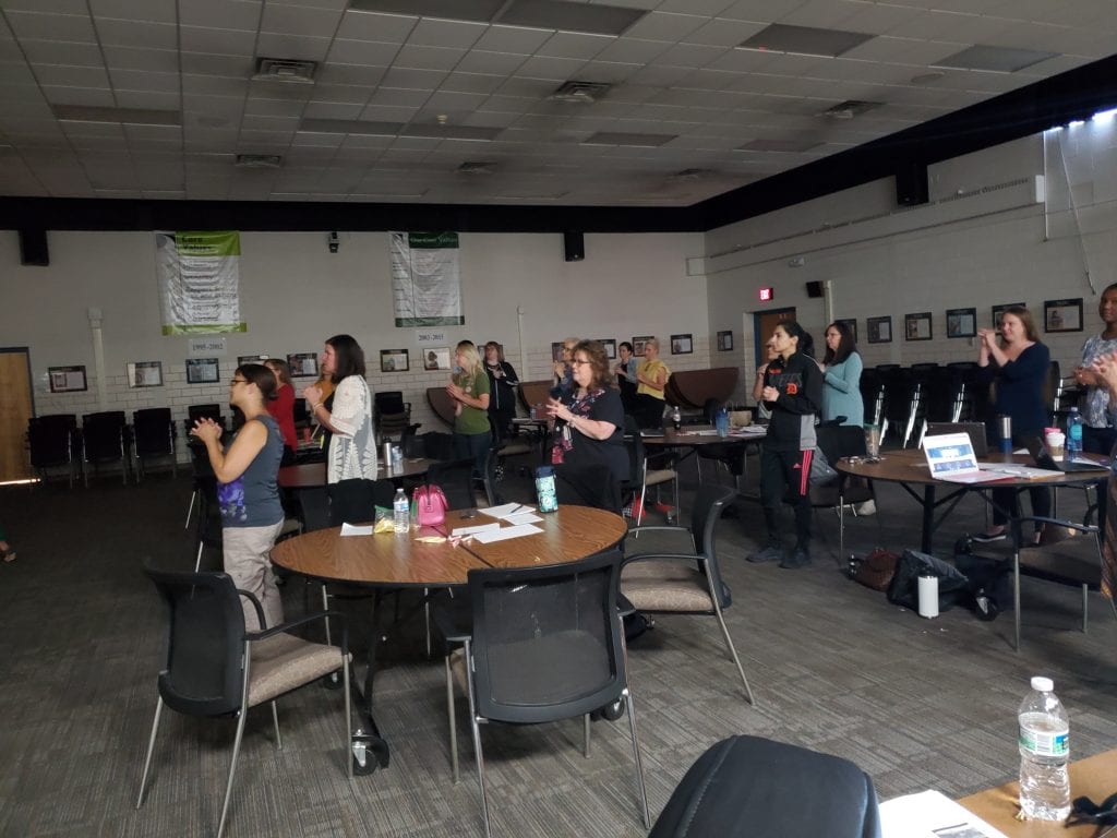 teachers standing using hand gestures to learn about the brain during a SDI training