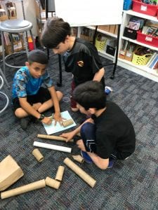 3 boys use toilet paper rolls to create a project