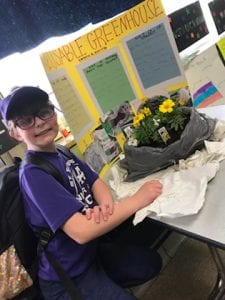 boy showing plant for science project