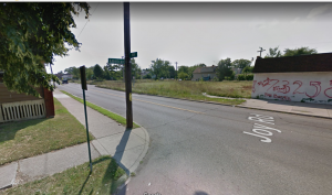 Google Image of the corner of America St. and Joy Road. Shows intersection with building covered in graffiti. 