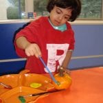 Student painting a mini pumpkin
