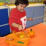 Student painting a mini pumpkin