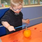 Student painting a mini pumpkin
