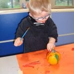 Student painting a mini pumpkin