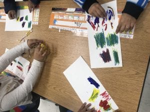 student hands mixing colors on a white paper