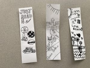 three white bookmarks with black marker drawings on them