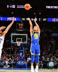 image of Stephen Curry shooting a basketball; another player is trying to raise their hands to block the ball