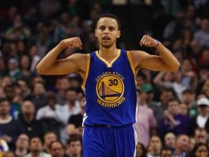 image of Stephen Curry in a Warriors uniform standing in front of a crowd holding his hands above his shoulders