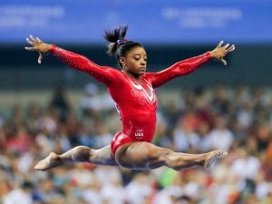 image of Biles leaping through the air wearing a red leotard