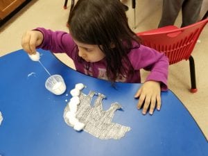 We loved dipping the cotton balls in the glue! We reused clean laundry detergent caps for glue cups!
