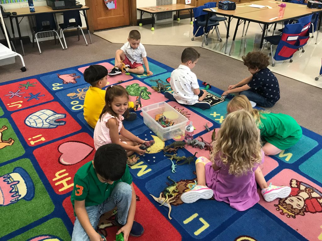 A group of students on the carpet working with dinosaurs
