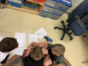 three students working on drawing their drafts of the wind turbines